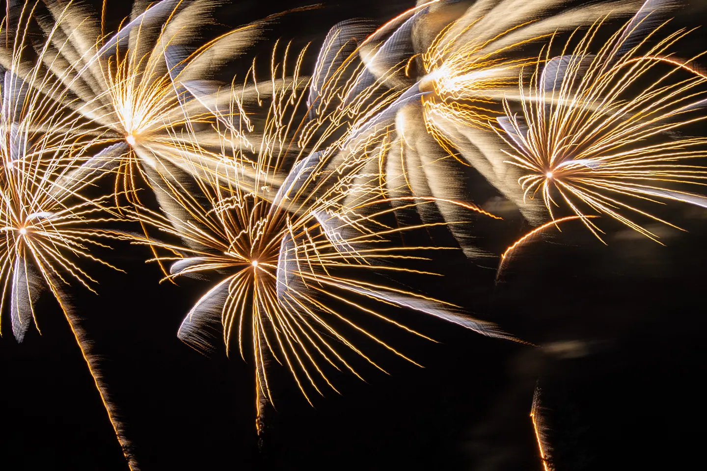 Flowing gold fireworks forming layered arcs in the night