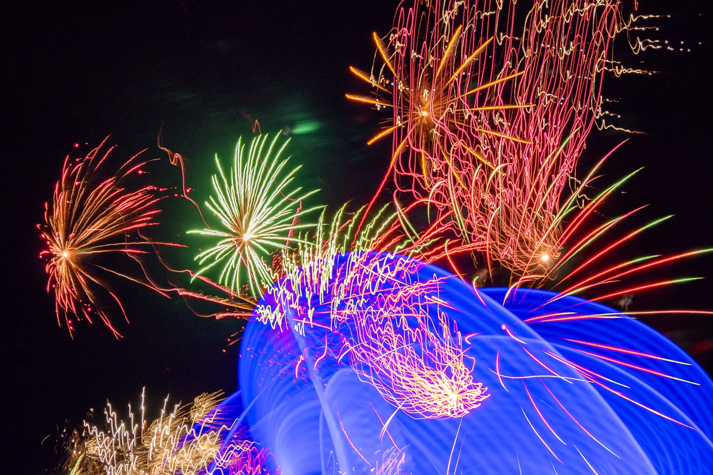Red, green, gold, and electric blue light trails from fireworks